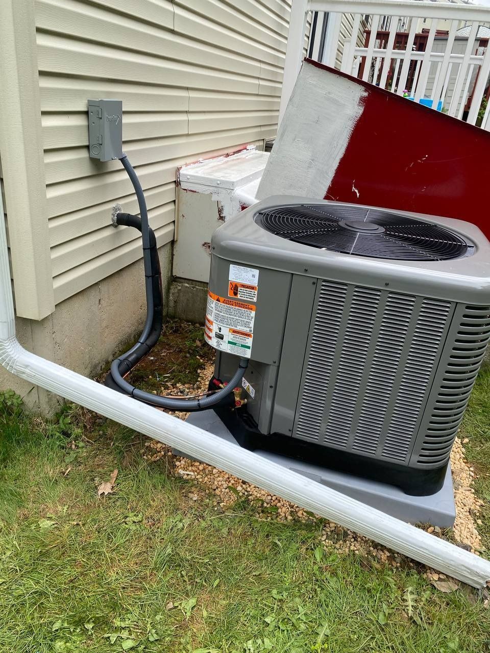 An air conditioning unit next to a house with a power connection.