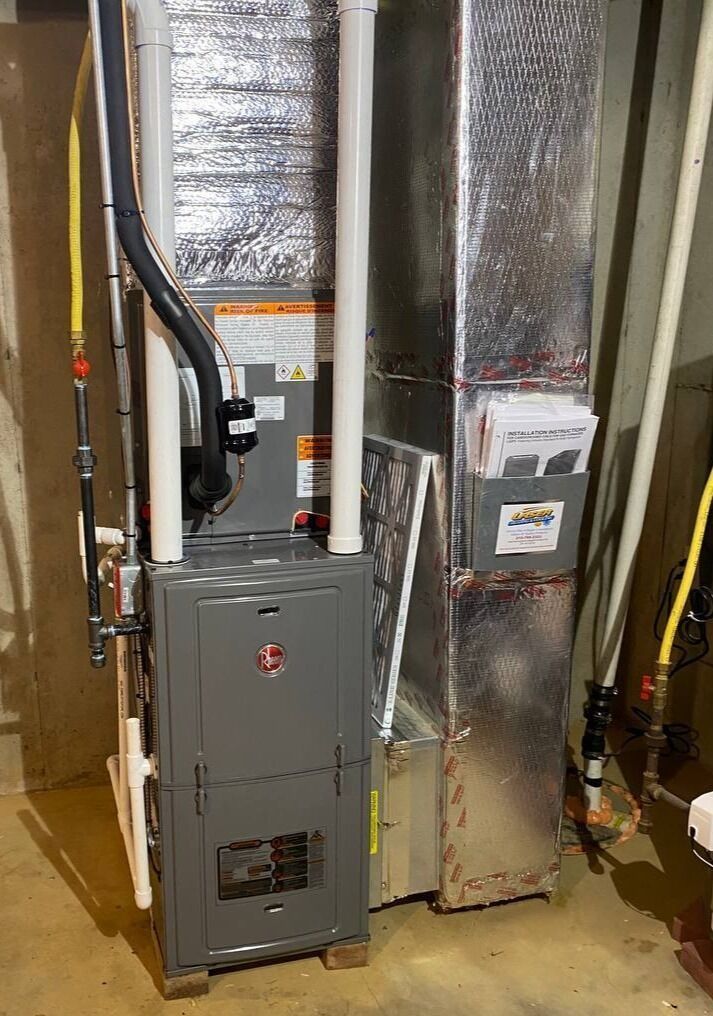 A Rheem furnace in a basement. Ductwork and pipes are visible.