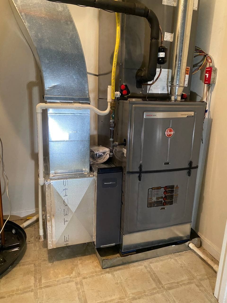 Furnace unit in a corner, with ductwork and a humidifier. Gray metal with various pipes and vents.