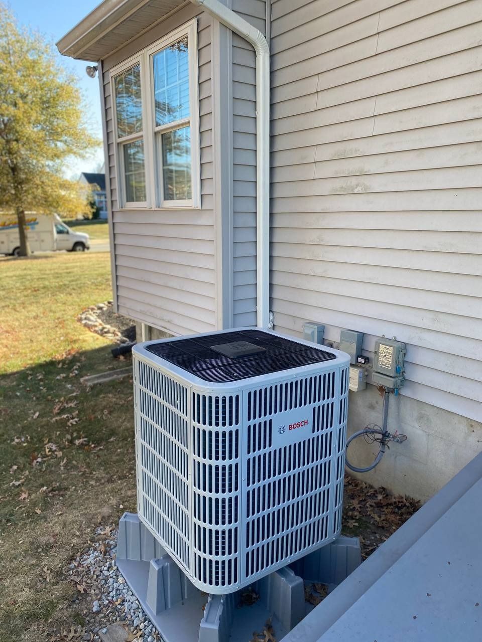 An air conditioning unit next to a house with siding and a window.
