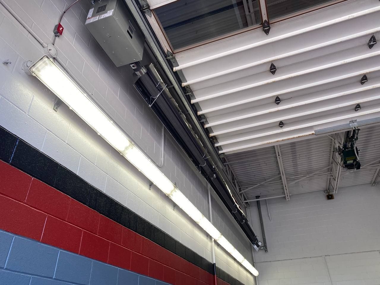 Fluorescent lights on wall; garage door tracks and ceiling lights overhead.