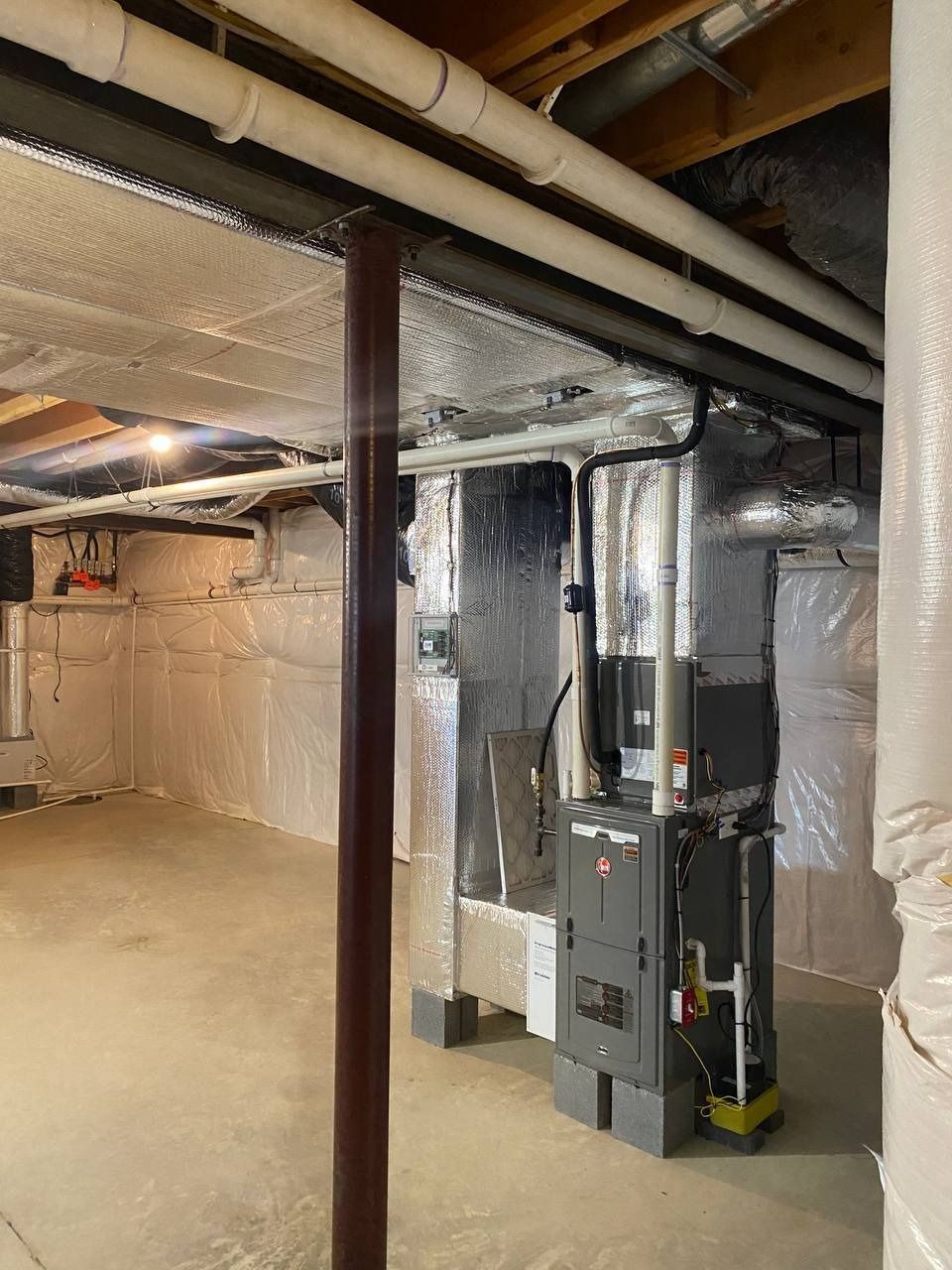 Finished basement with silver insulation, HVAC system, and exposed pipes.