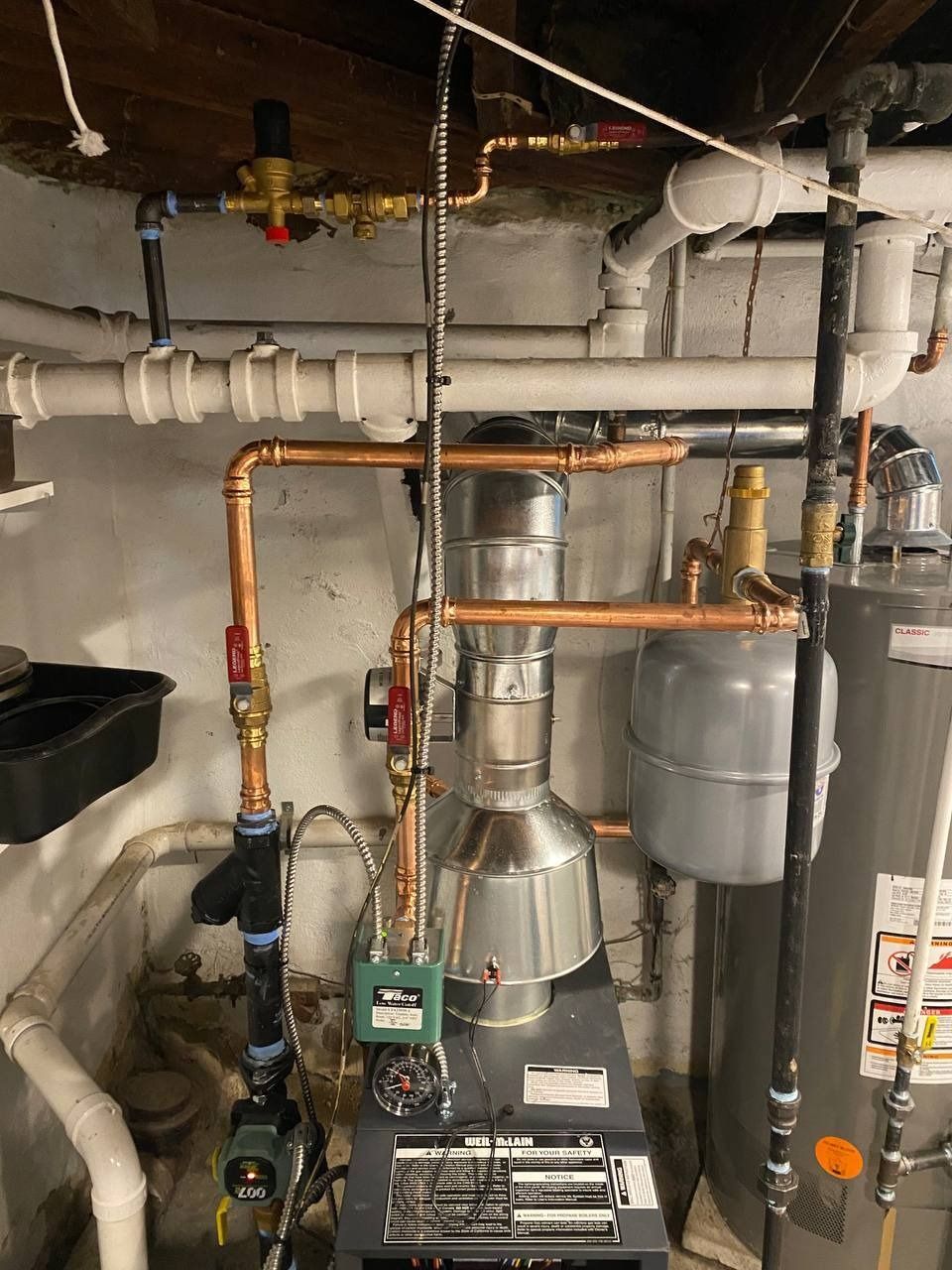 Plumbing system with copper pipes, furnace, water heater, and various gauges and valves in a basement setting.