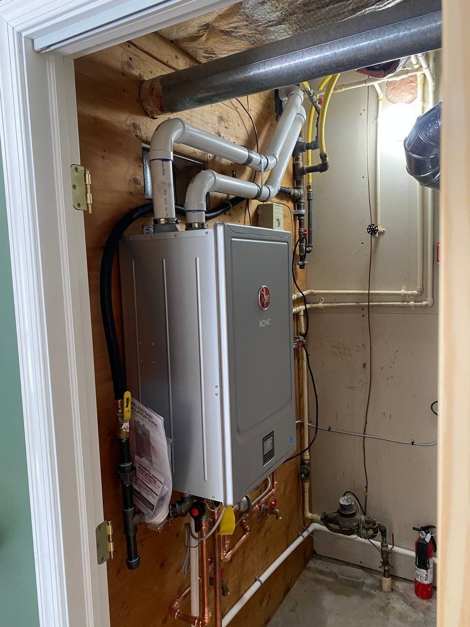 A tankless water heater installed in a closet, with associated pipes and venting.