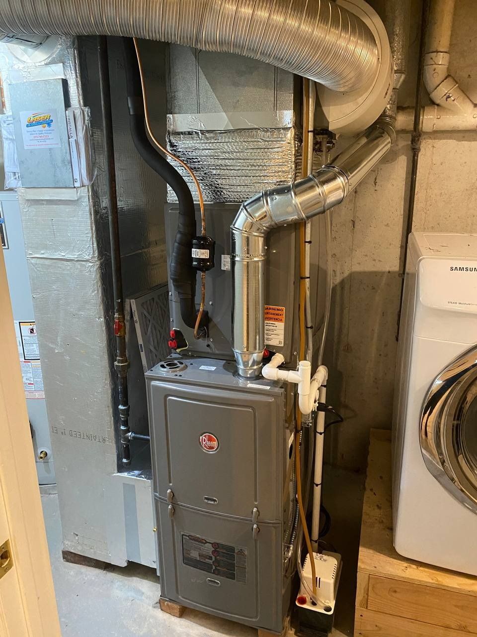Furnace in a utility room with ductwork, vents, and a washing machine nearby.