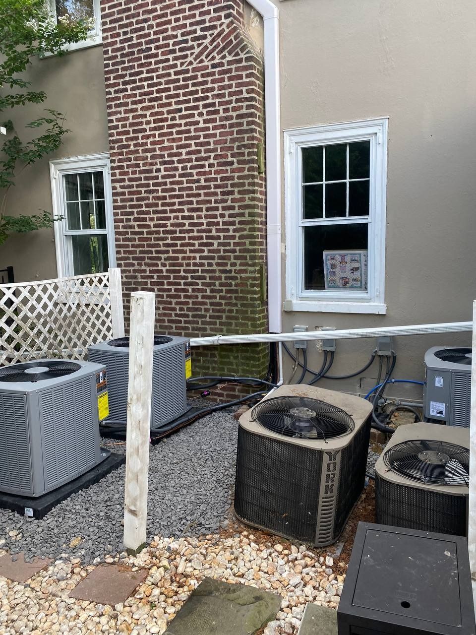 Backyard with several air conditioning units, brick chimney, and windows.