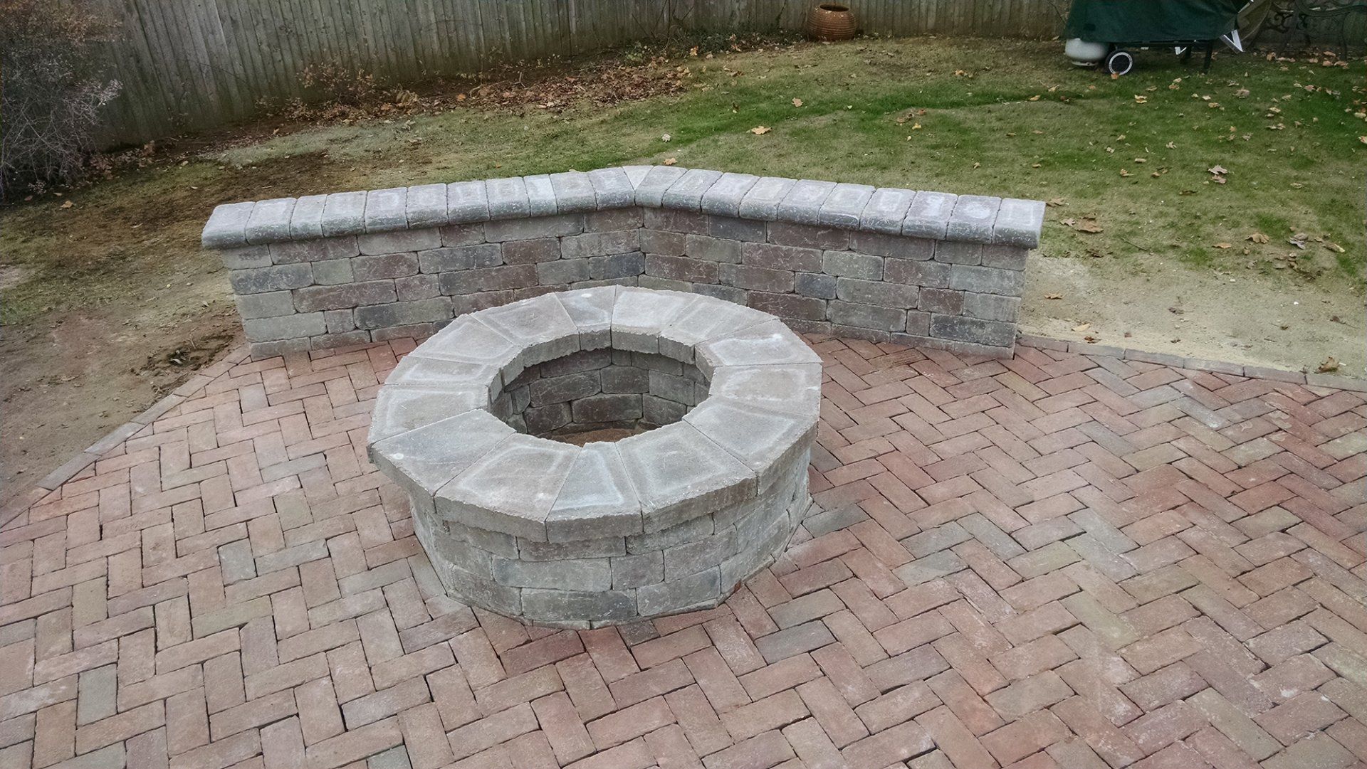 A fire pit is sitting on top of a brick patio