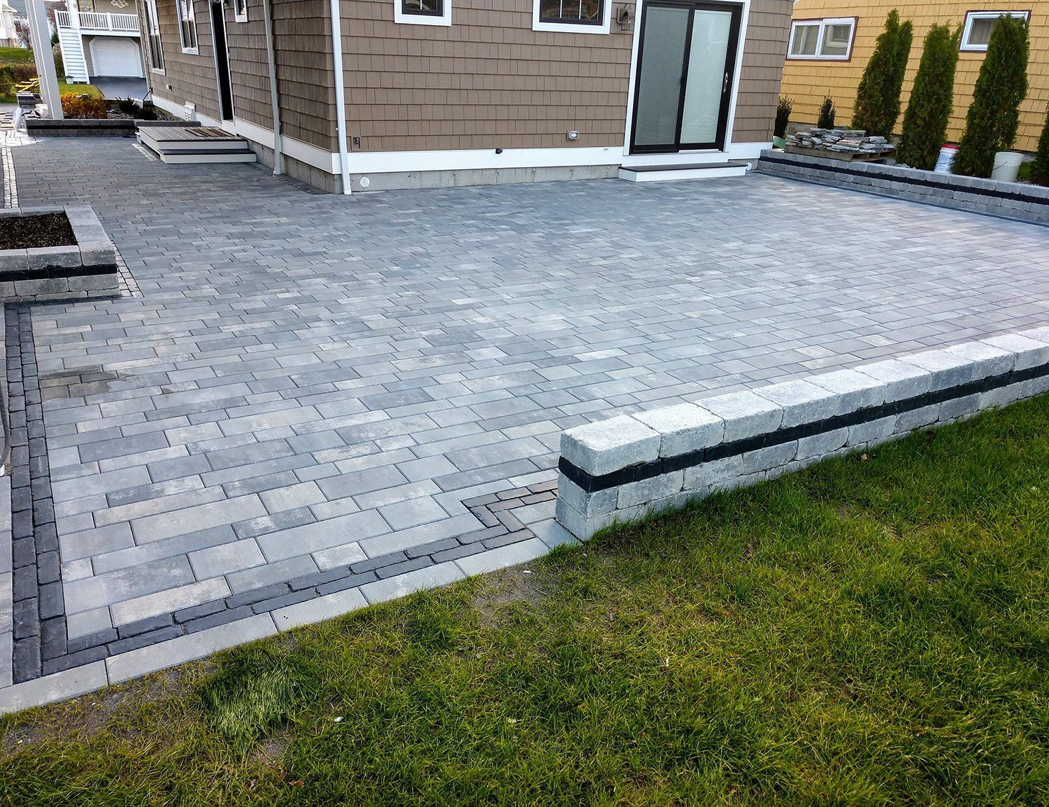 A patio with a brick walkway in front of a house