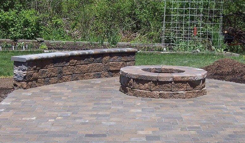 A brick patio with a fire pit in the middle