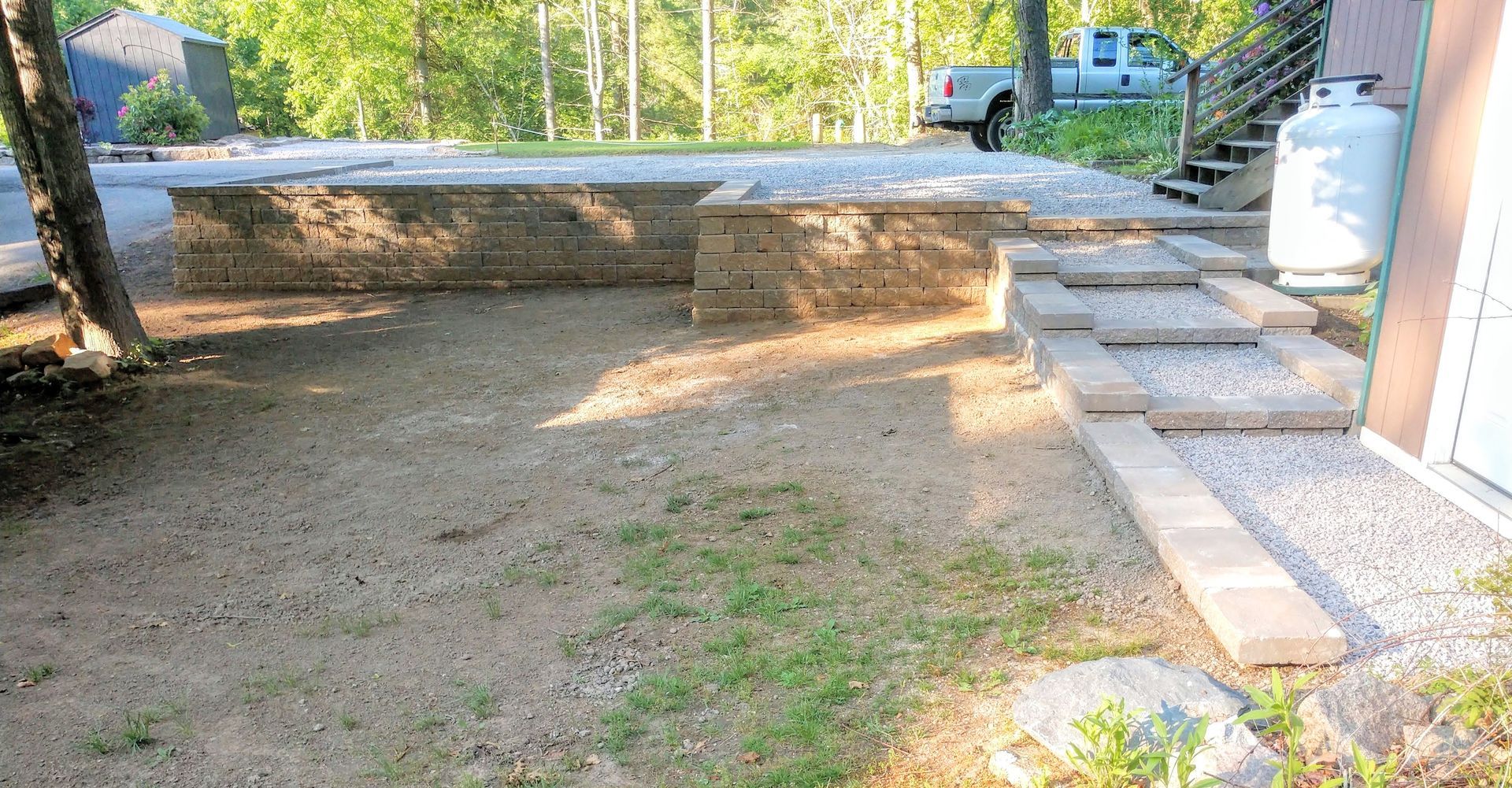 A backyard with a stone wall and steps leading to a house.