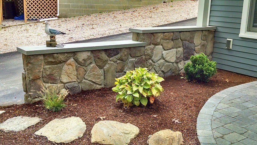 A stone wall with stepping stones in front of a house
