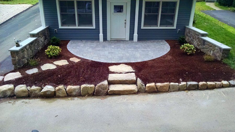 A blue house with a stone walkway leading to the front door