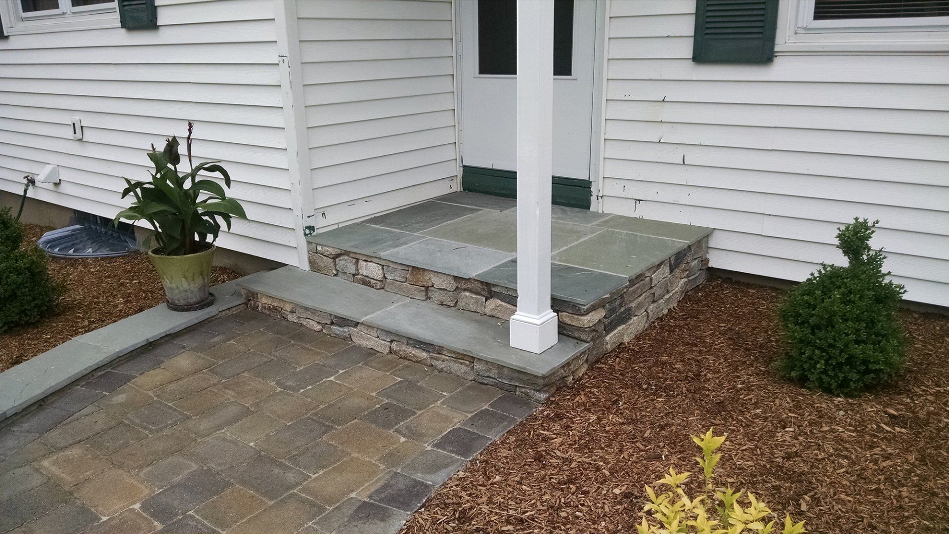 A white house with a stone porch and steps