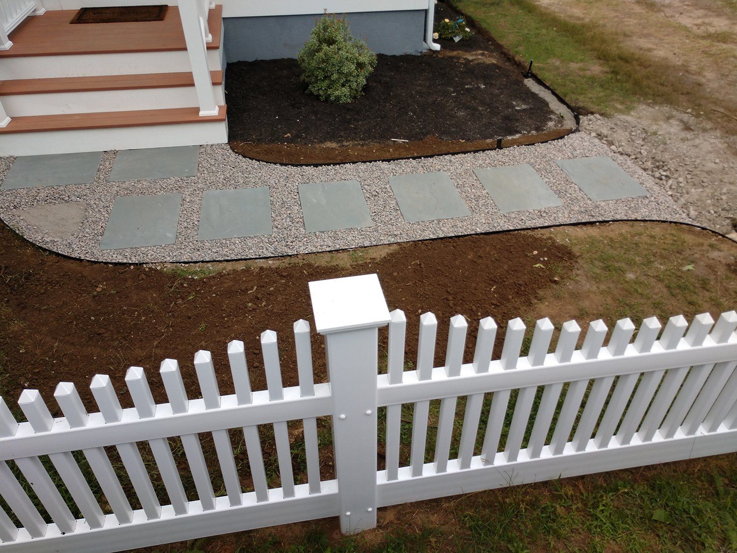 A white picket fence is in front of a house
