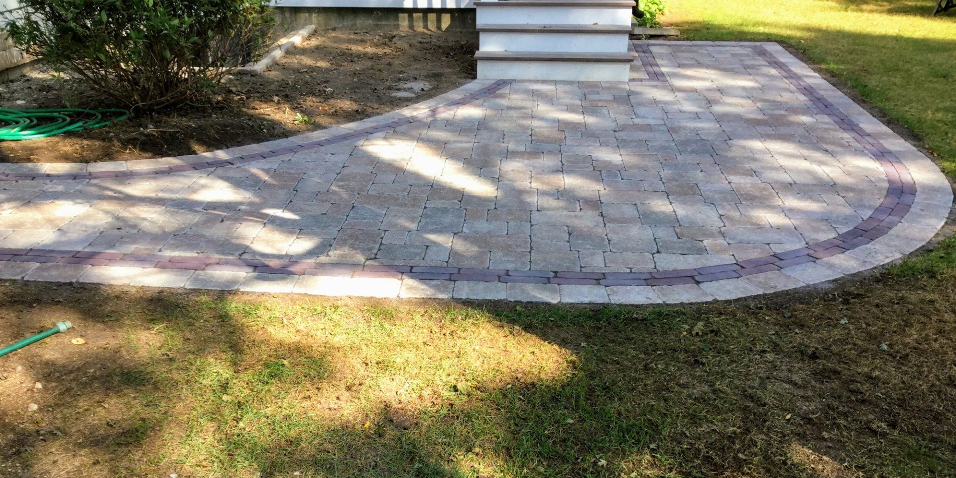 A brick walkway is sitting on top of a lush green lawn in front of a house