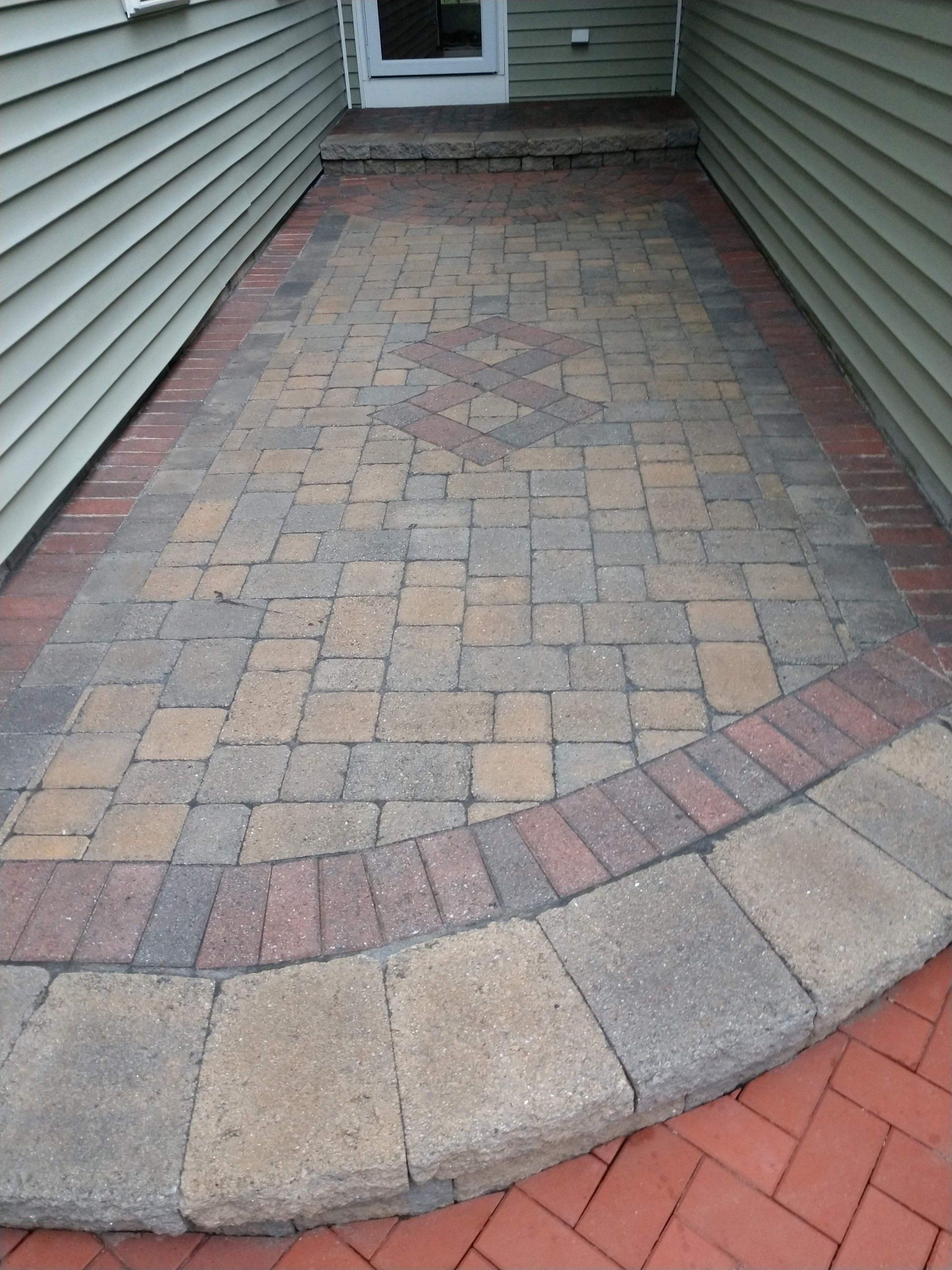 A brick walkway leading to a doorway in a house