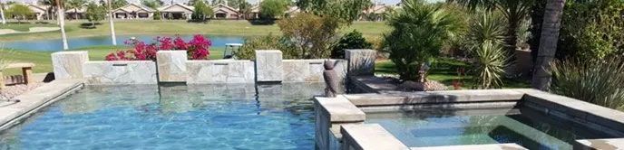 A large swimming pool with a hot tub in the middle of it surrounded by trees.