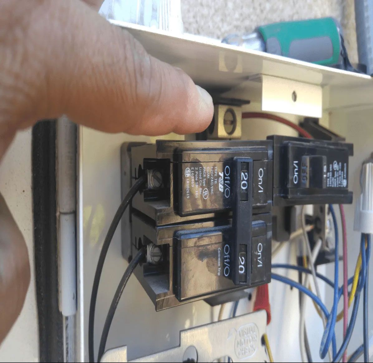 A person is plugging a 20 amp breaker into a box