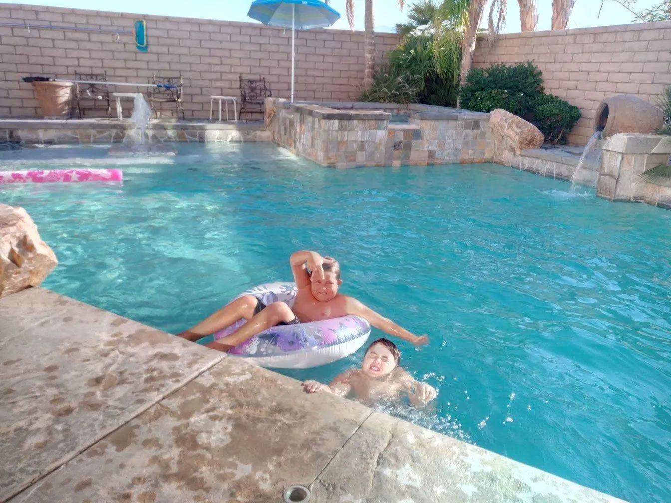 A man and a child are floating in a swimming pool.