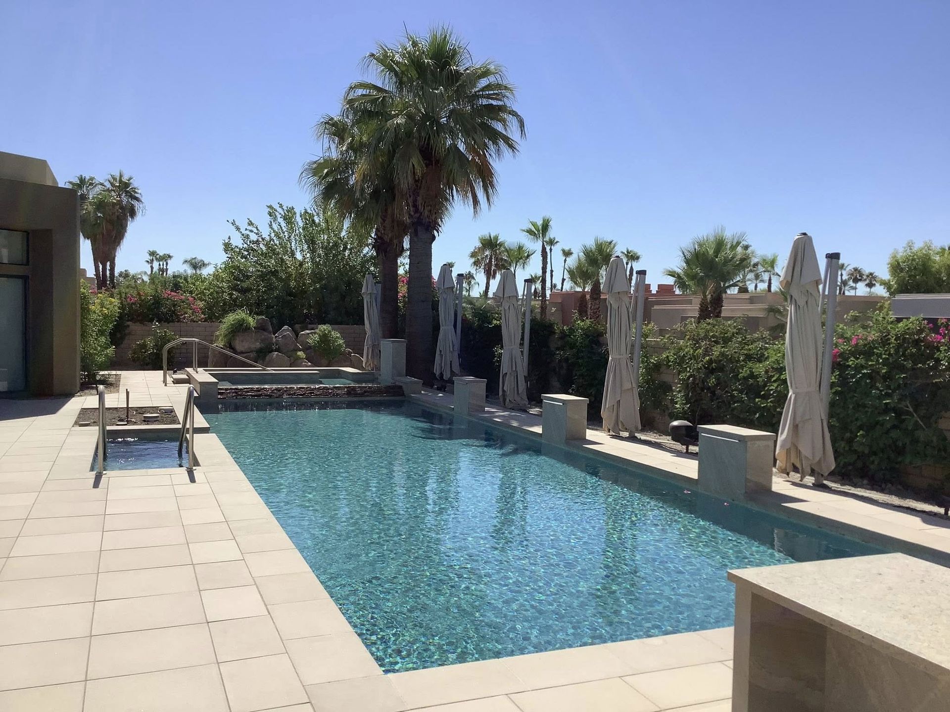 A large swimming pool surrounded by palm trees and umbrellas