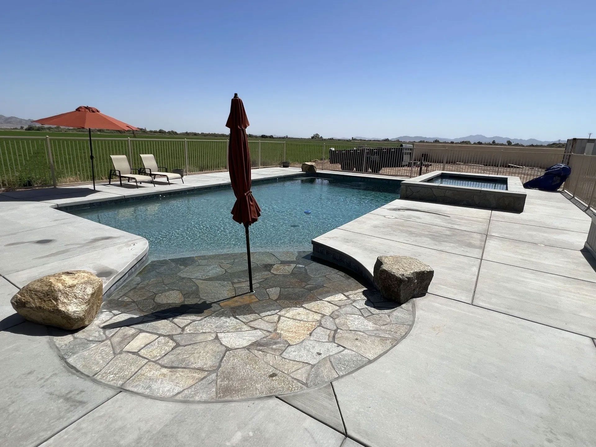 A large swimming pool with a red umbrella in the middle