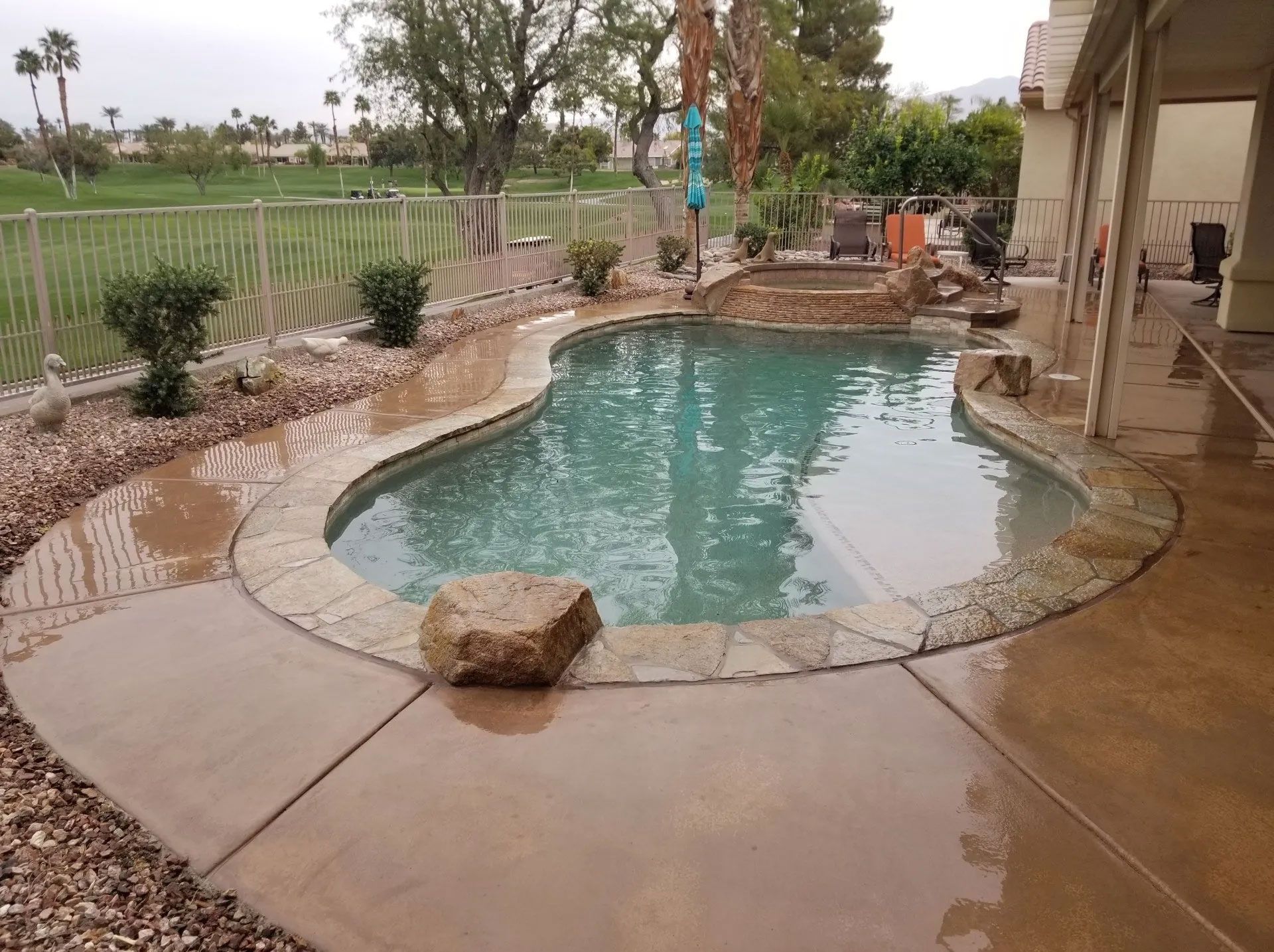 A large swimming pool with a large rock in the middle of it
