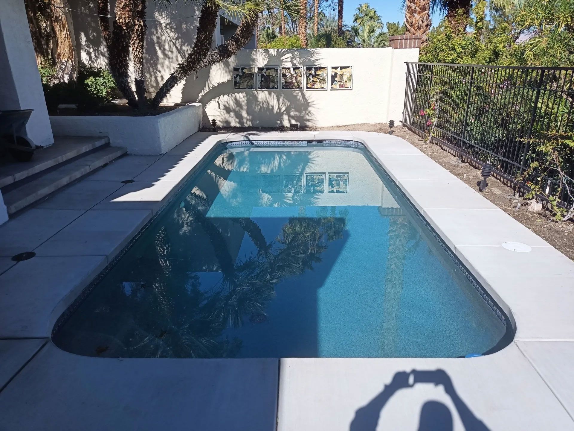 A shadow of a person taking a picture of a swimming pool