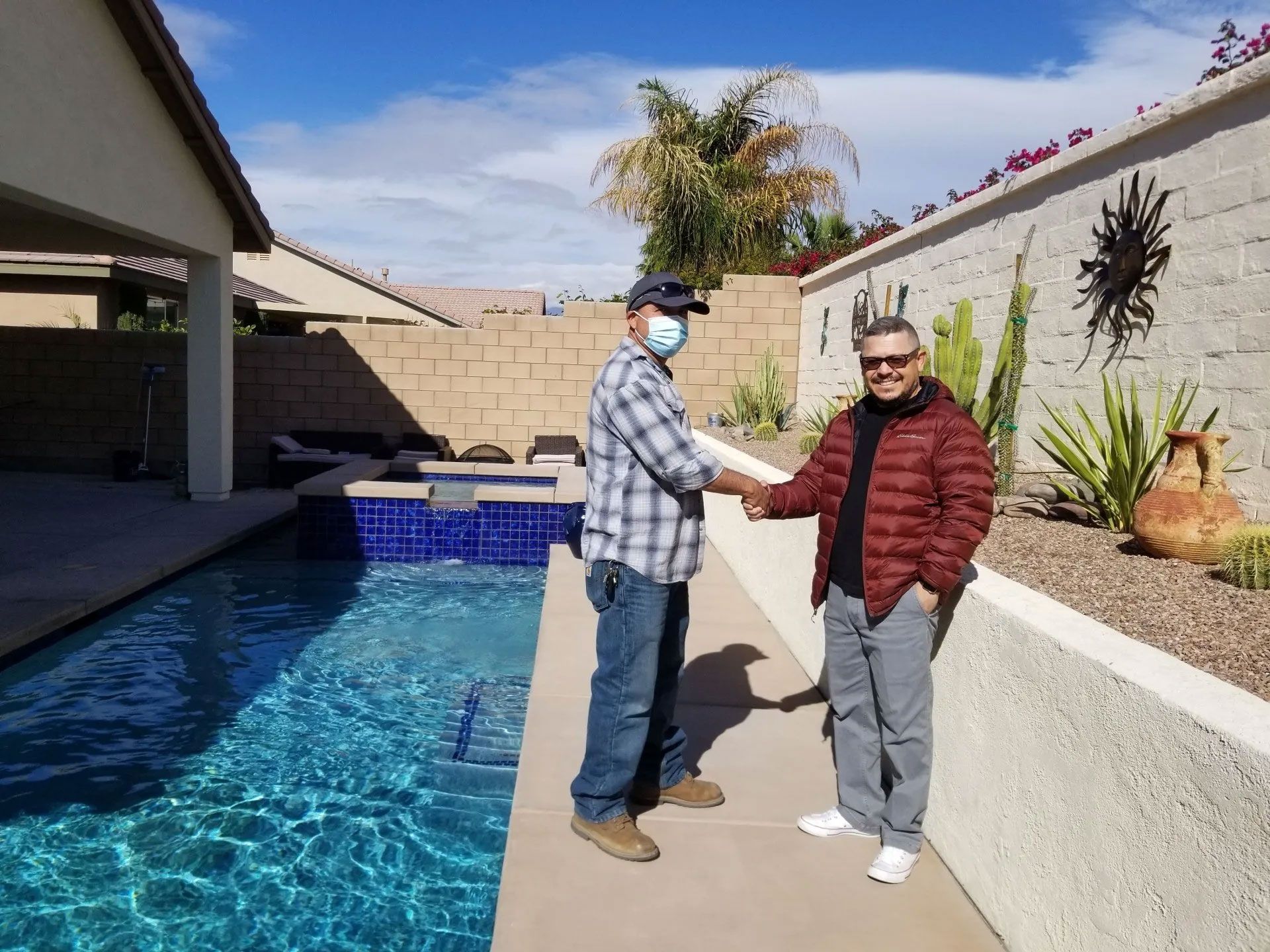 Two men shaking hands in front of a swimming pool