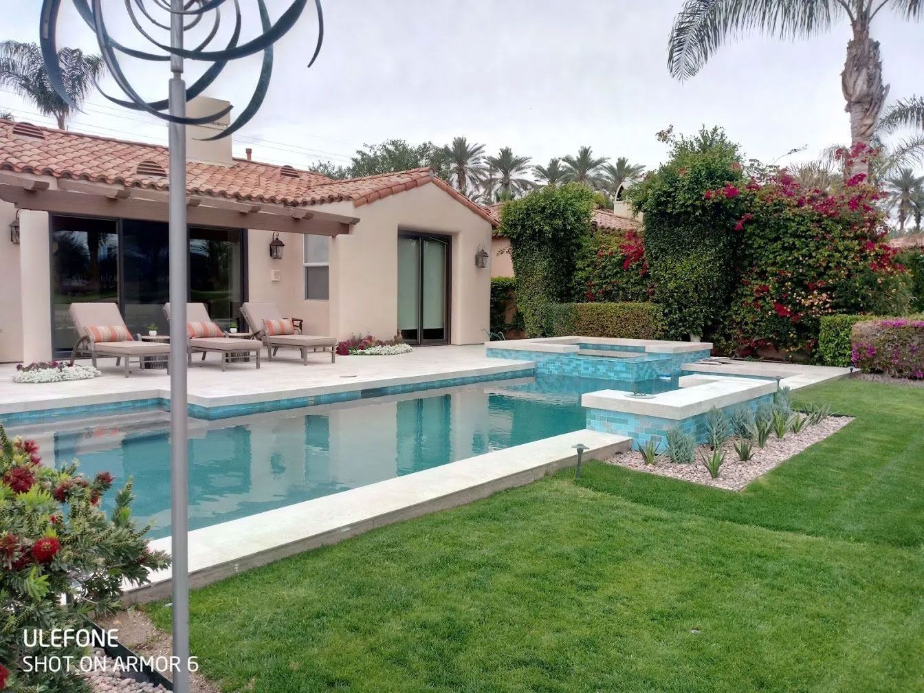 A large swimming pool is in the backyard of a house.