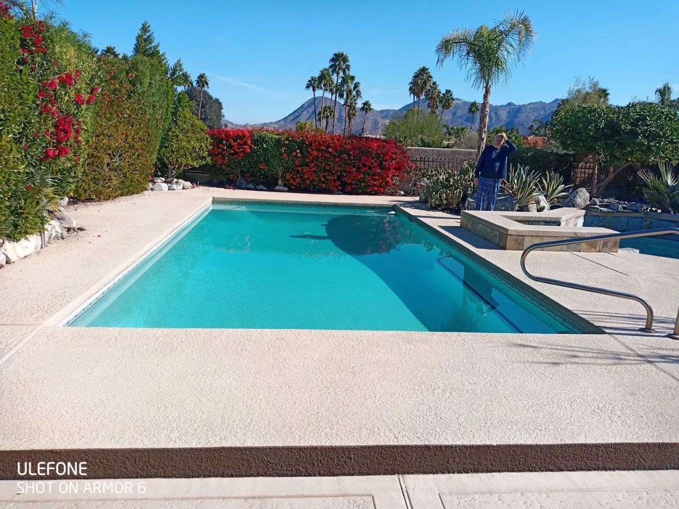 A man is standing next to a large swimming pool
