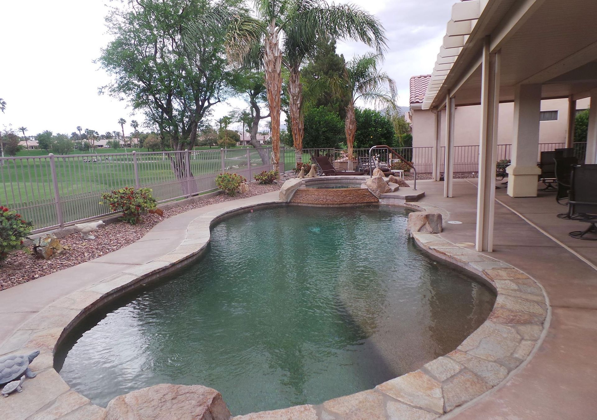 A large swimming pool is surrounded by rocks and trees