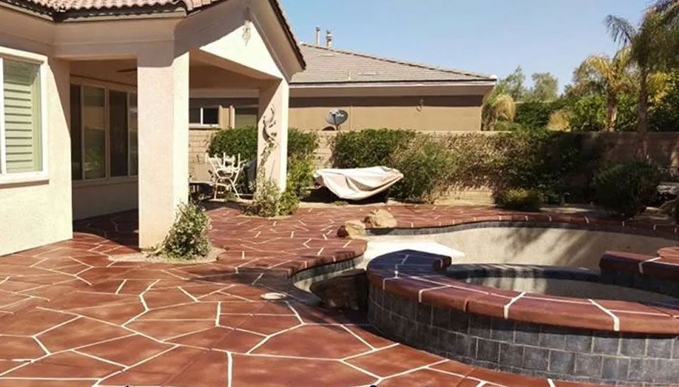 A patio with a pool and a house in the background