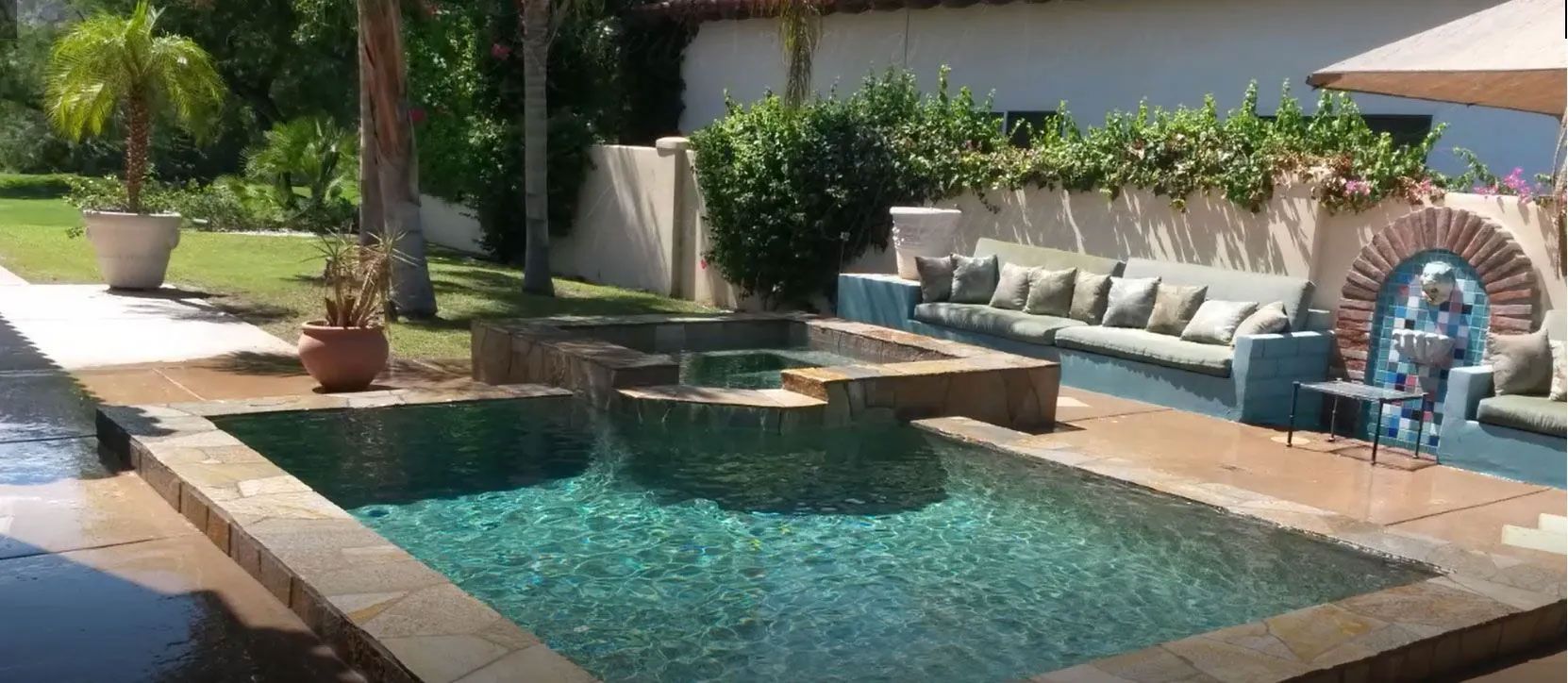 There is a large swimming pool in the backyard of a house.