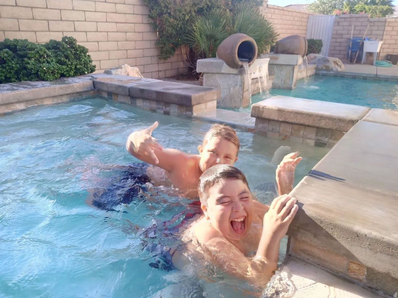 Two young boys are playing in a swimming pool.