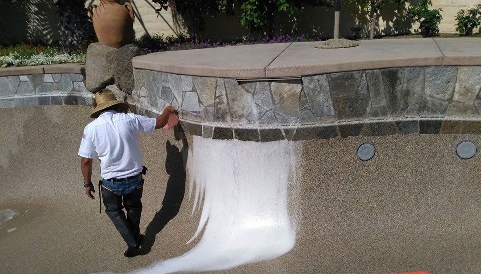 A man in a cowboy hat is painting a pool