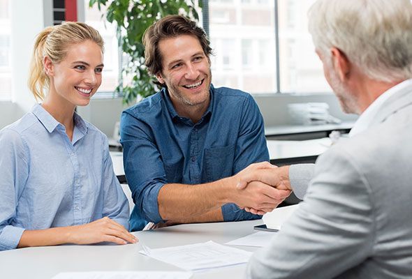 A man and woman are shaking hands with a man while sitting at a table.