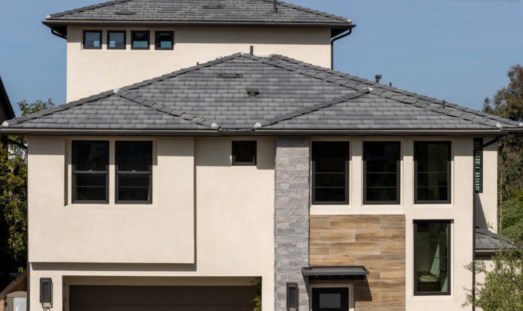 A large white house with a gray roof and a lot of windows.