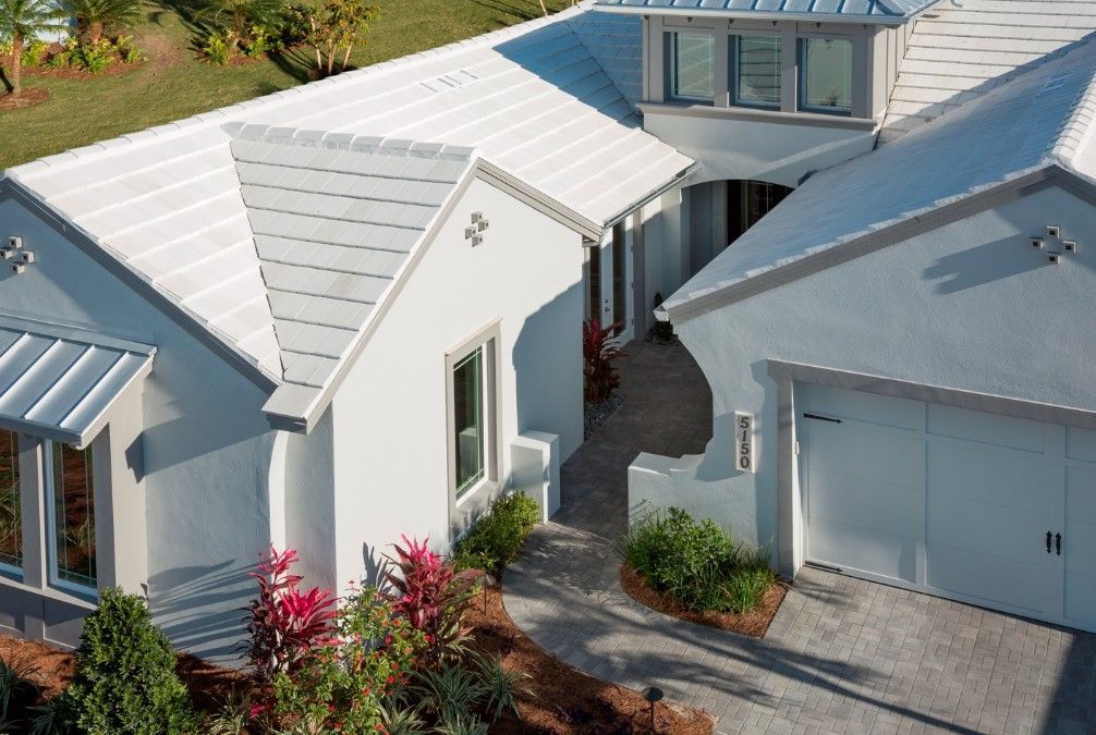 An aerial view of a white house with a metal roof