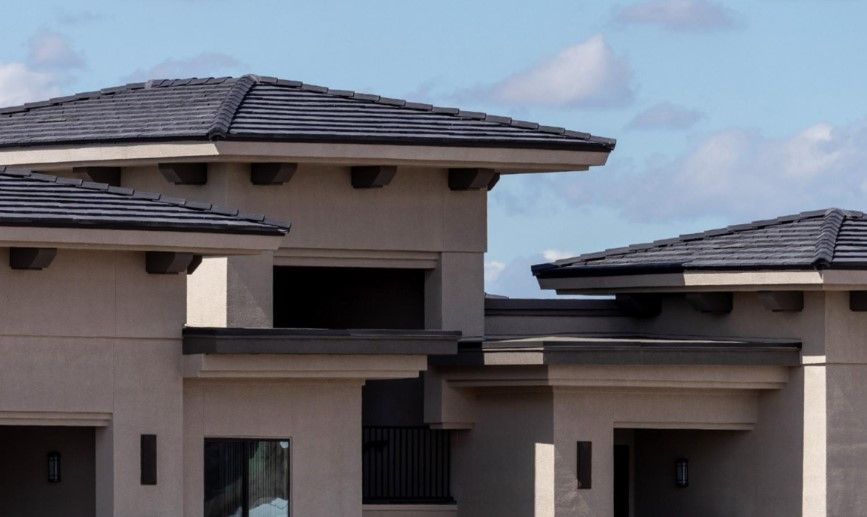 A large house with a black roof and a blue sky in the background
