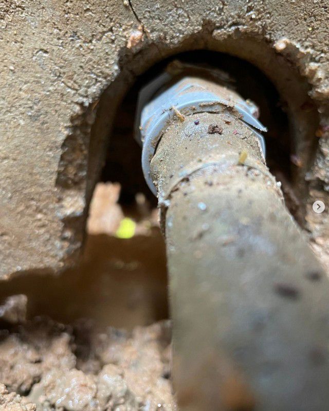 A close-up of a pipe fitting in a hole in a wall, secured with white tape.