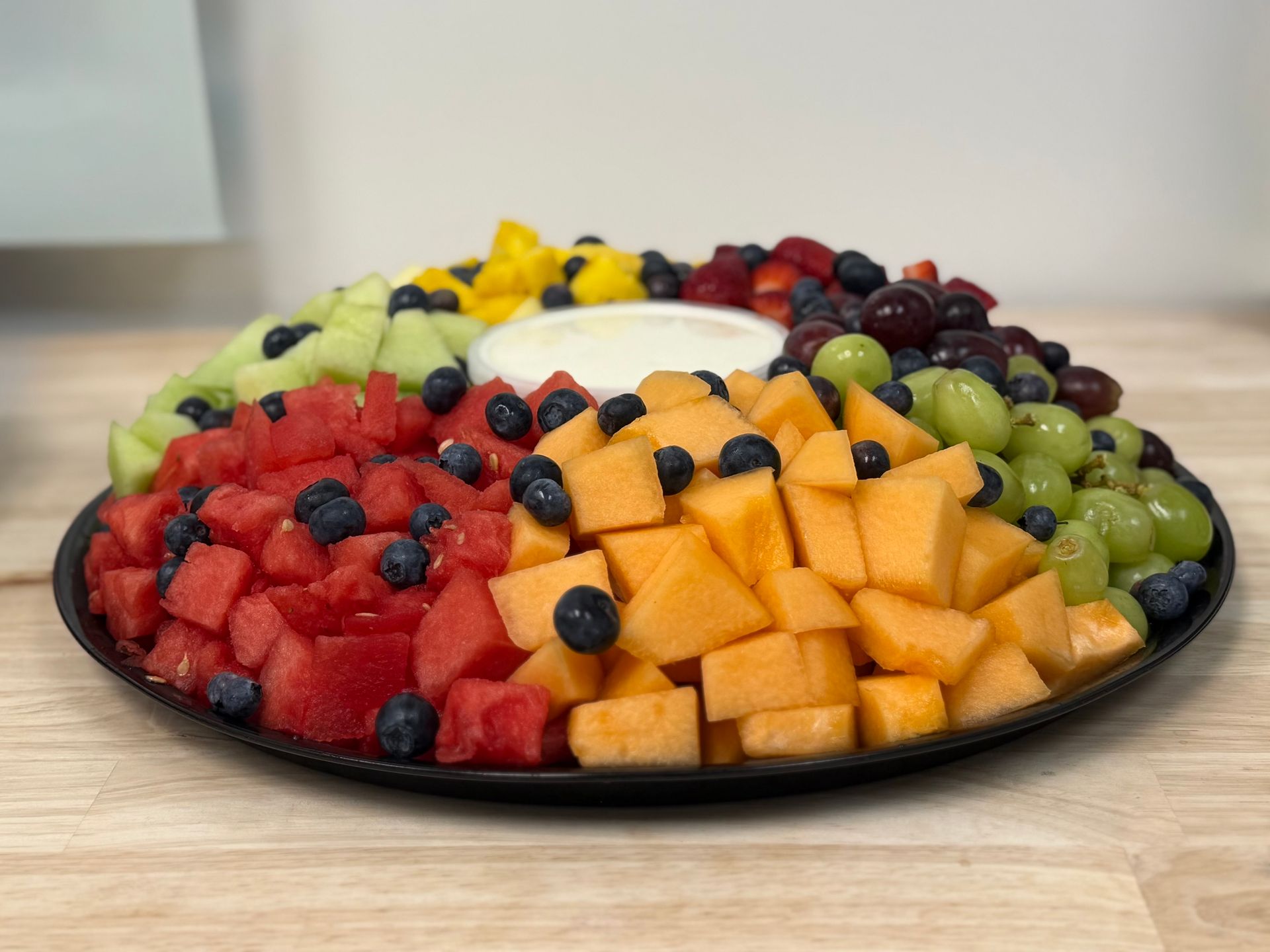 Fruit platter with cubed melon, strawberries, grapes, and blueberries arranged in a colorful ring