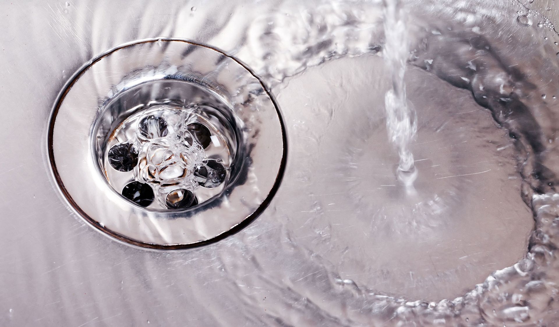 A close up of a sink drain with water running down it.