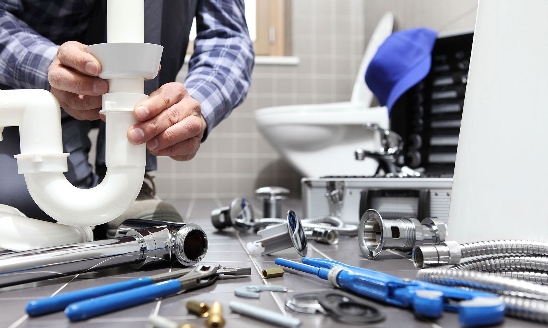 A plumber is working on a sink pipe in a bathroom.