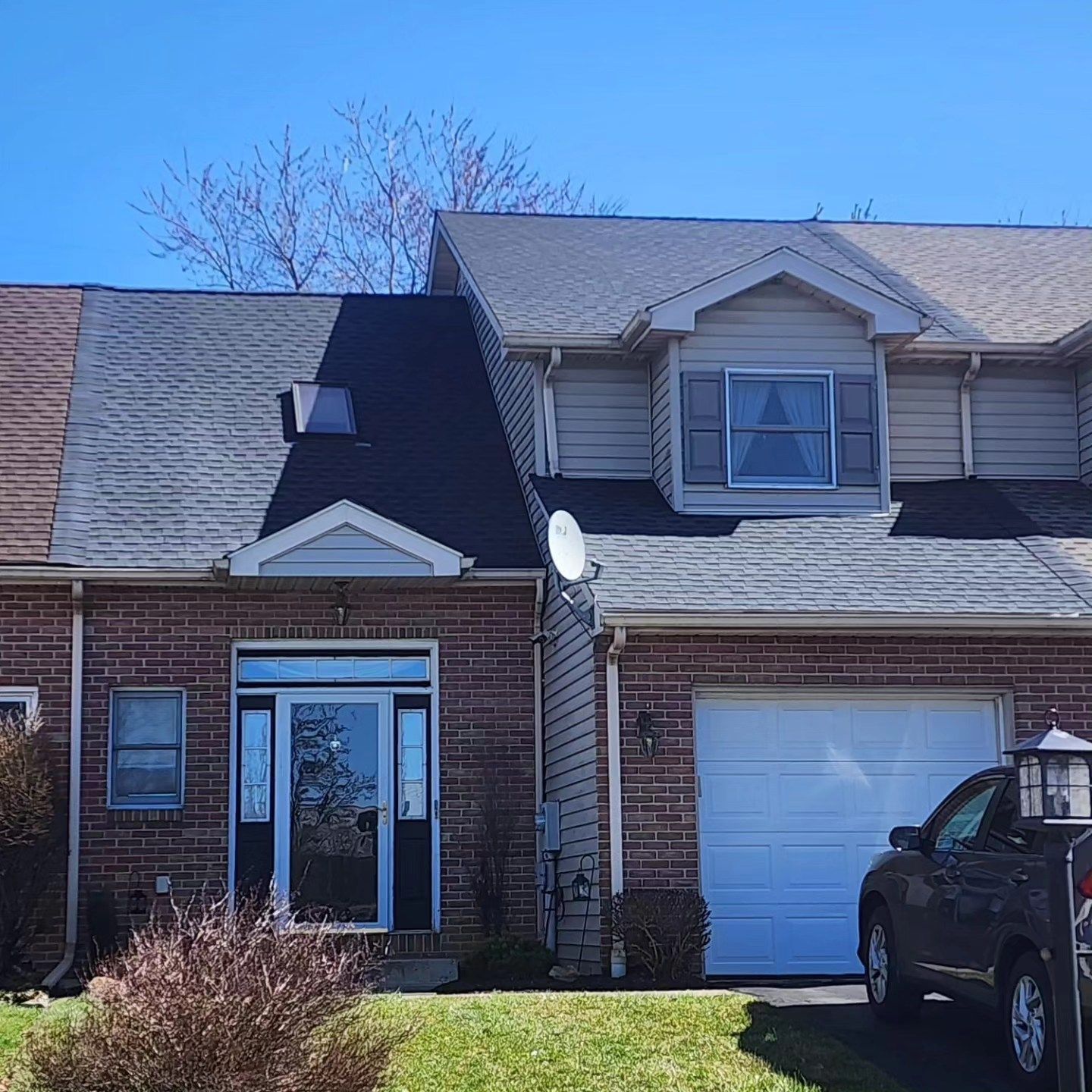 Townhomes with brick and siding exteriors; one with a garage and satellite dish.