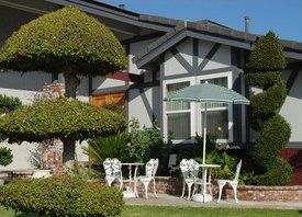 house with chairs, umbrella and shaped trees infront