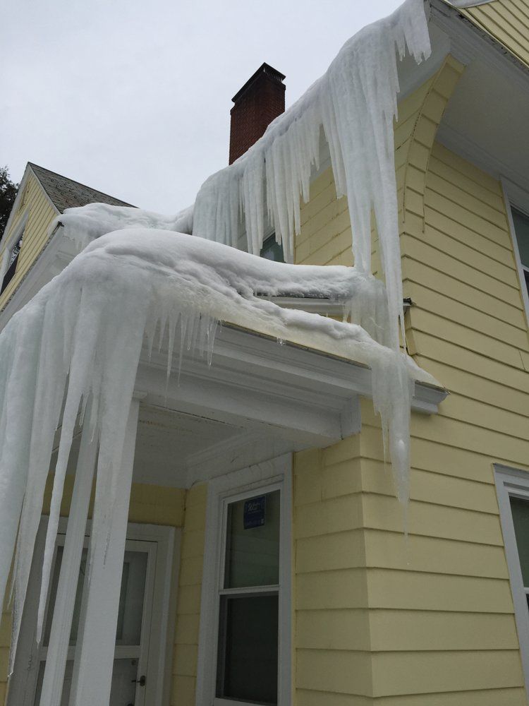 Icicles hanging from a yellow house roof and porch in winter.
