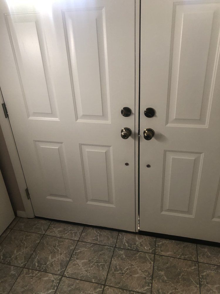 White double front door with dark handles above a tiled entryway.
