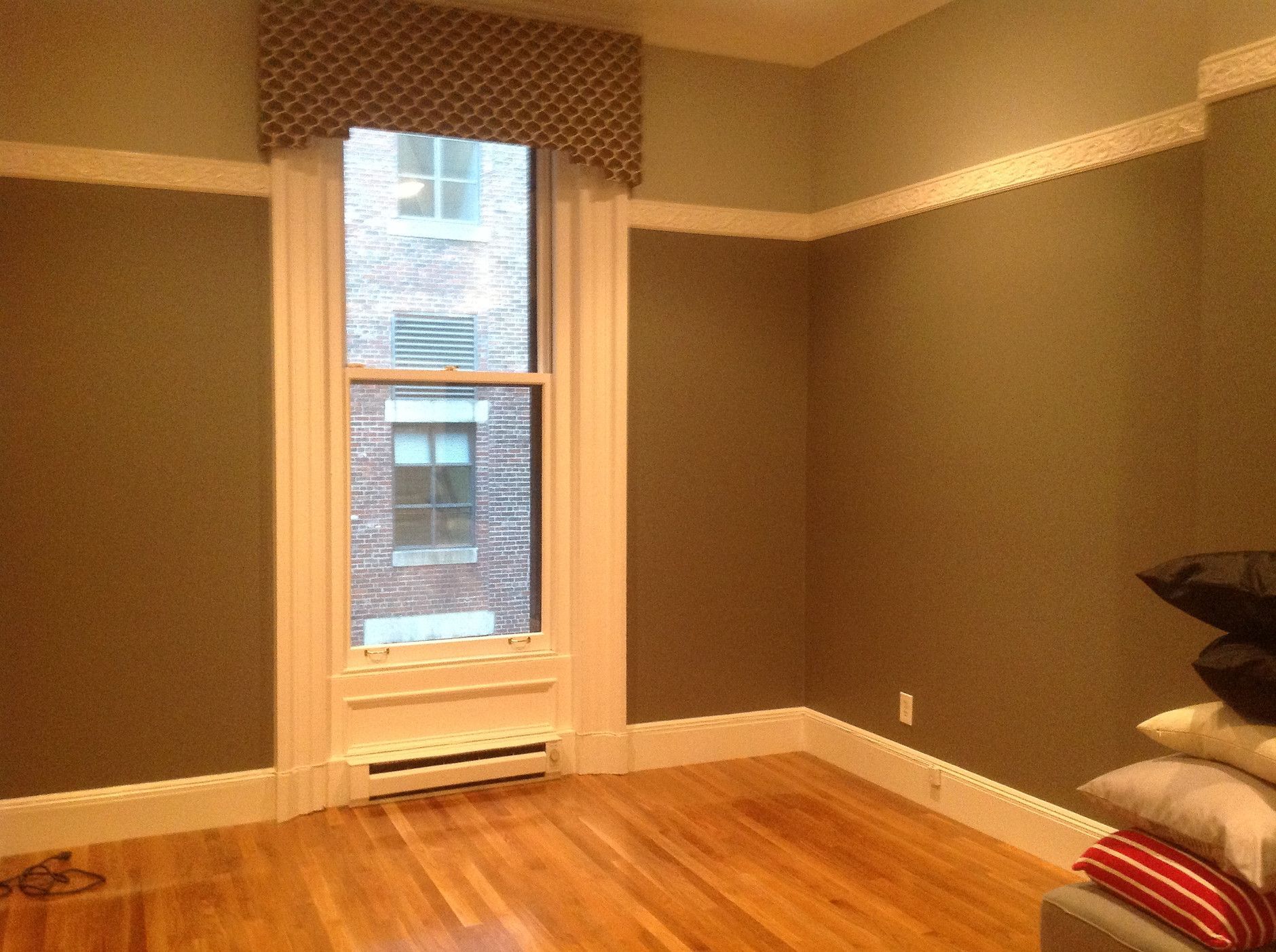 Empty room with hardwood floor, gray walls, and a tall window with white trim.
