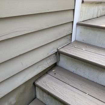 Weathered gray wooden stairs beside beige house siding