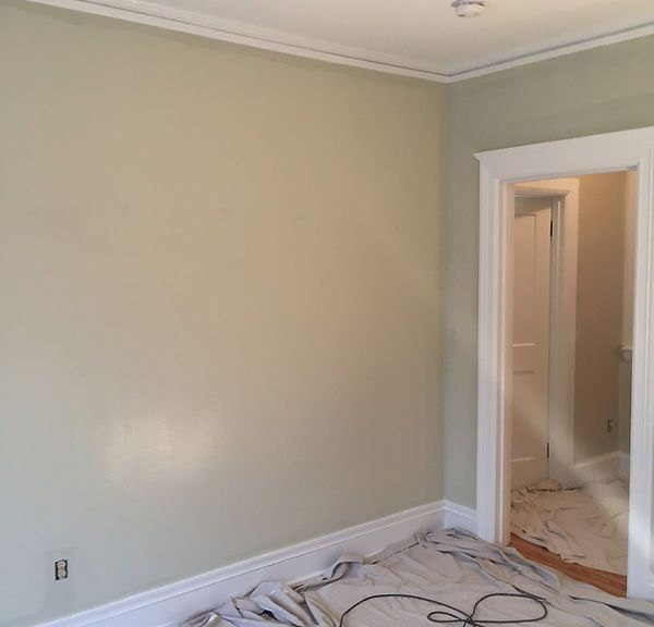 Empty beige room with white trim, open doorway, and construction debris on the floor